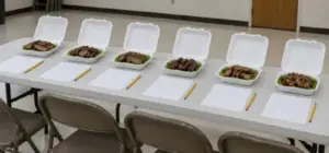 Blind judging table with six identical turn-in boxes and blank scoring forms