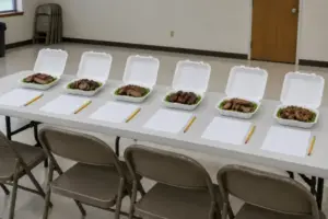 Blind judging table with six identical turn-in boxes and blank scoring forms