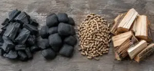 Lump charcoal, briquettes, hardwood pellets and wood chunks side by side