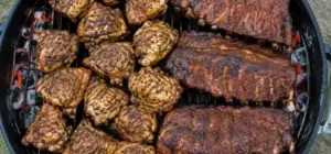 Charcoal grill grate fully loaded with chicken thighs and racks of ribs